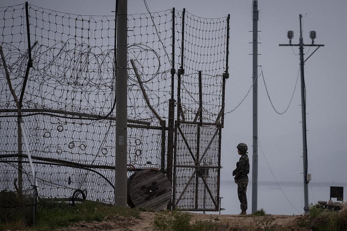 A South Korean soldier standing guard at an opening to the fence of the Demilitarised Zone (DMZ) on Gyodong, a tiny outlying island near to the west of Seoul. At its closest point, Gyodong island lies barely 2km from North Korea, with residents subje