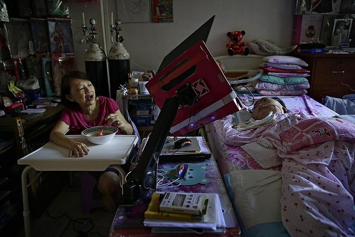 Madam Yong has a bowl of oats for lunch in the bedroom while chatting with Ms Goh, who uses her laptop with eye-control software. Ms Goh taught her mother how to use the computer and mobile phone. Says Madam Yong: "If I didn't have her, I wouldn't ha