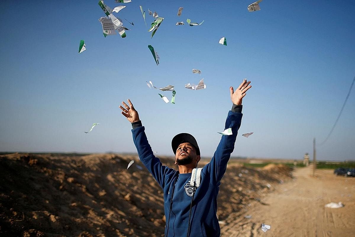 Left: An Israeli man confronts a Palestinian woman in Jerusalem as Israeli settlers celebrate Jerusalem Day.Far left: A Palestinian protester throwing away leaflets dropped by the Israeli military at the Israel-Gaza border yesterday. Above: Palestini