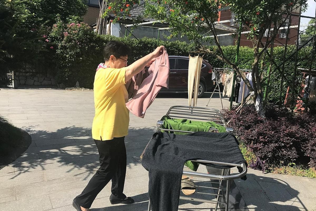 Madam Wang Guifen hangs her clothes to dry. While a hired cleaner cleans the house twice a week, simple chores are done by the Zhus and the tenants. Mealtimes are a lively, social affair, and there is a good spread of vegetables, meat, poultry and se