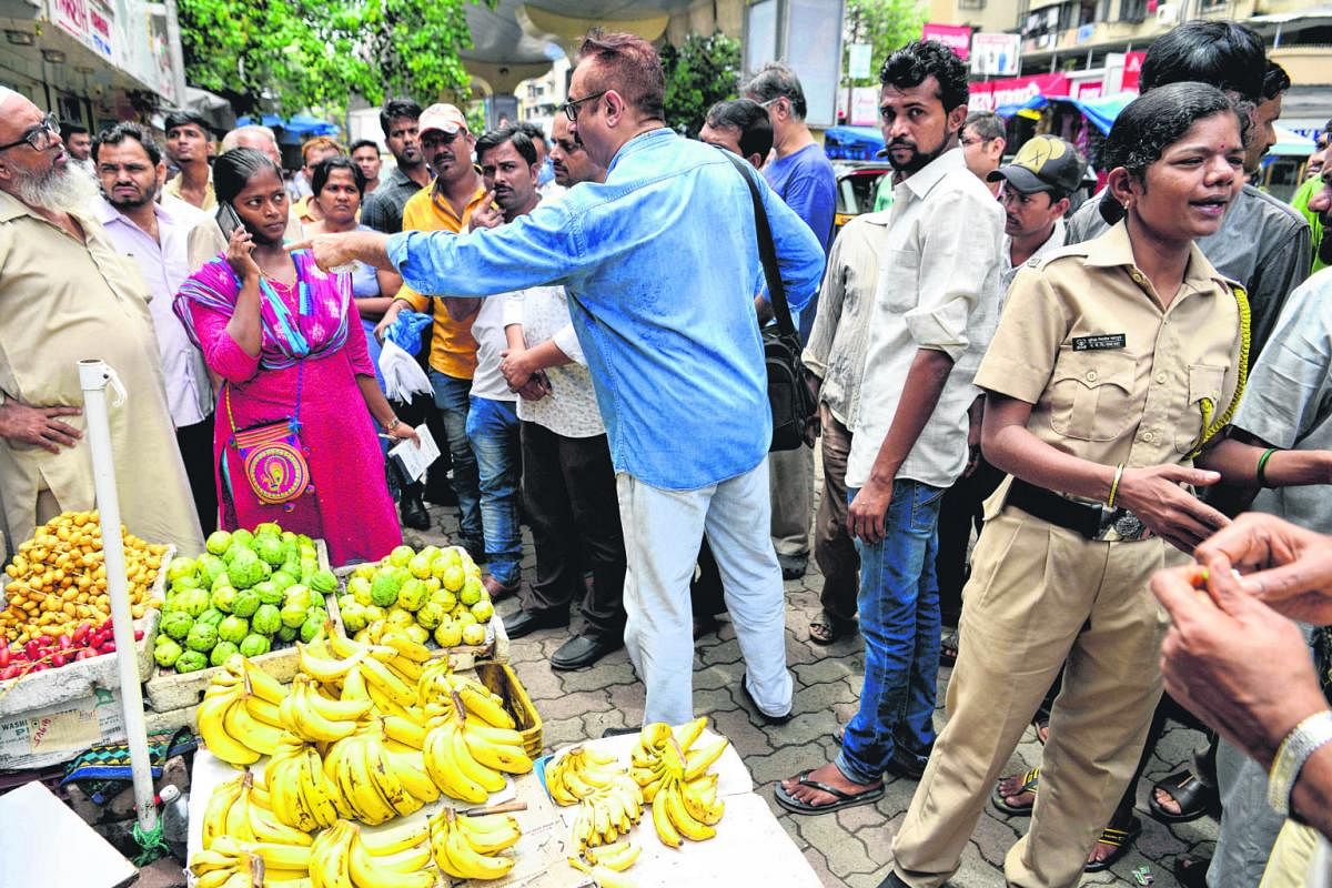 Indian shopkeepers arguing with a city official (in pink) as she fines a fruit seller for using plastic bags under 50 microns in thickness in Mumbai, which implemented a ban on single-use plastics from June 23. An Indian labourer carrying a sack of p