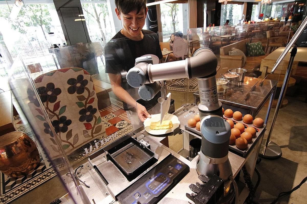 M Social Singapore hotel guest Eugene Pang getting an omelette cooked by AUSCA, a robotic egg chef at the breakfast buffet. Robot butlers Sophie (left) and Xavier (right) deliver items such as towels, toiletries and bottled water to the 223 guest roo