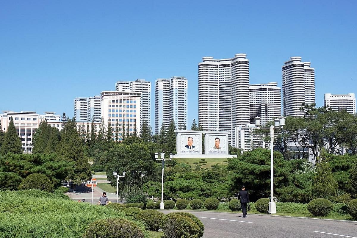 Left: The view of Pyongyang's central district from the Juche Tower lookout point. The high-rise flats were repainted en masse last month. Above: Student members of the Kimilsungist-Kimjongilist Youth League watch a live animal show at a dolphinarium