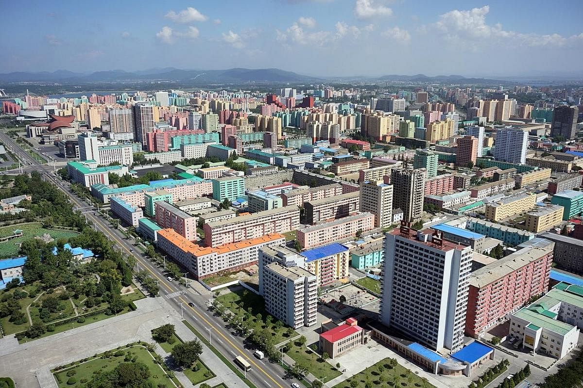 Left: The view of Pyongyang's central district from the Juche Tower lookout point. The high-rise flats were repainted en masse last month. Above: Student members of the Kimilsungist-Kimjongilist Youth League watch a live animal show at a dolphinarium