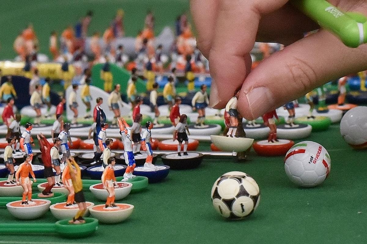 Isaac Lim (at left), 13, playing a friendly game with his father Bernard Lim, 46, while his brother Luke (face hidden), 15, acts as the referee. Memorabilia from over 10 years of competitions, these old Subbuteo footballs are now too brittle to play 