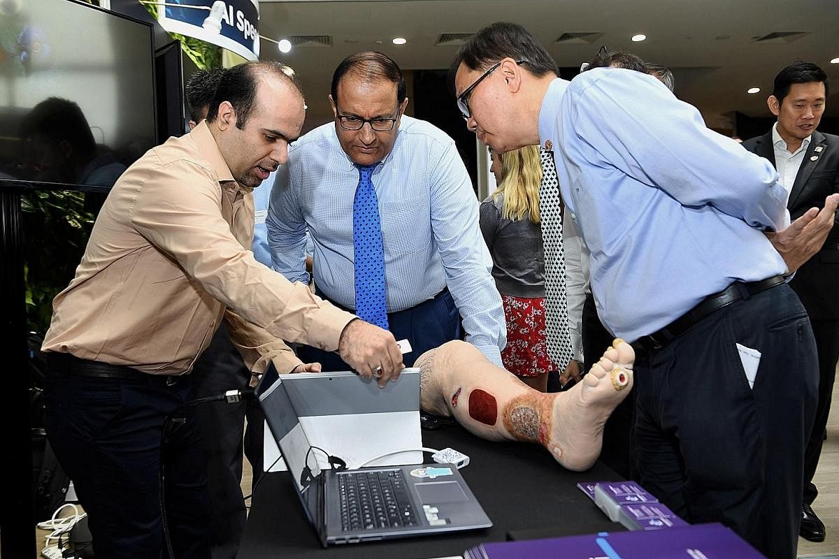 Minister for Communications and Information S. Iswaran (centre) observing a demonstration by KroniKare, which uses AI to assess wounds.