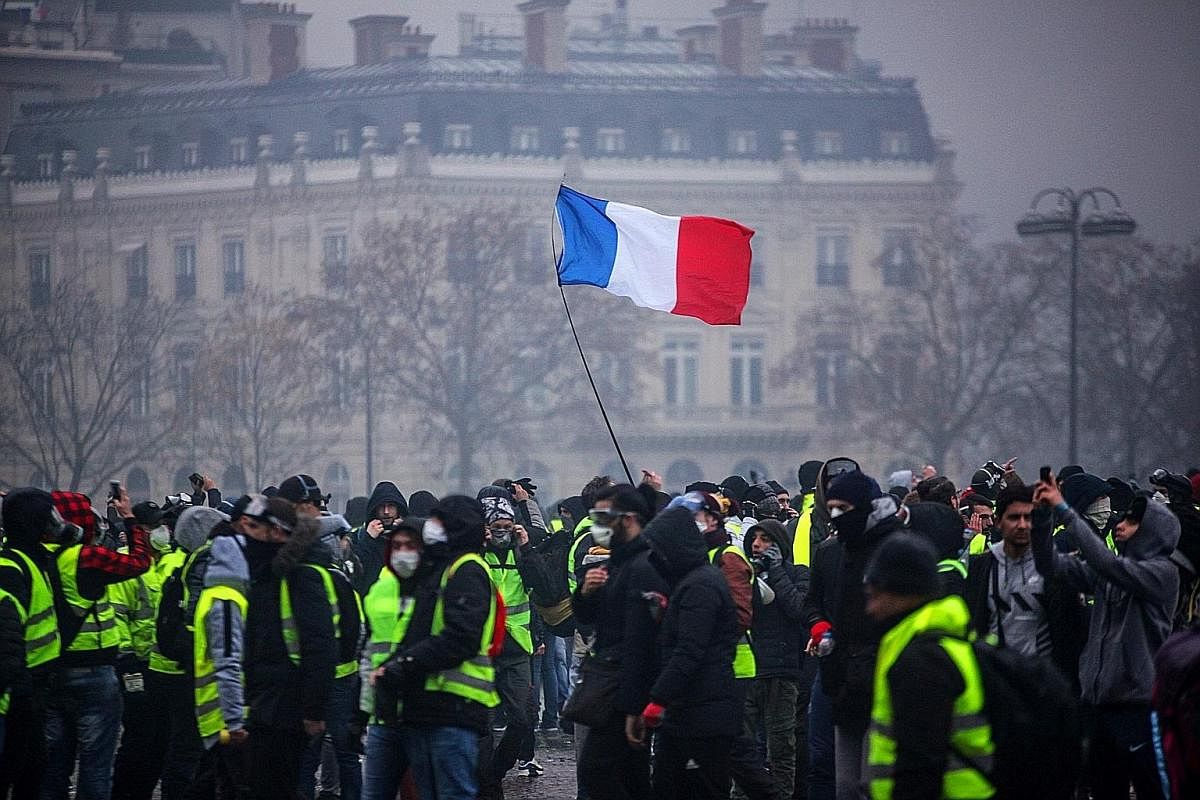 Demonstrators in France gathering near the Arc de Triomphe in Paris during a gilets jaunes (yellow vests) protest against rising oil prices and living costs this month. A woman with a stuffed rabbit toy found at her destroyed home in the earthquake a