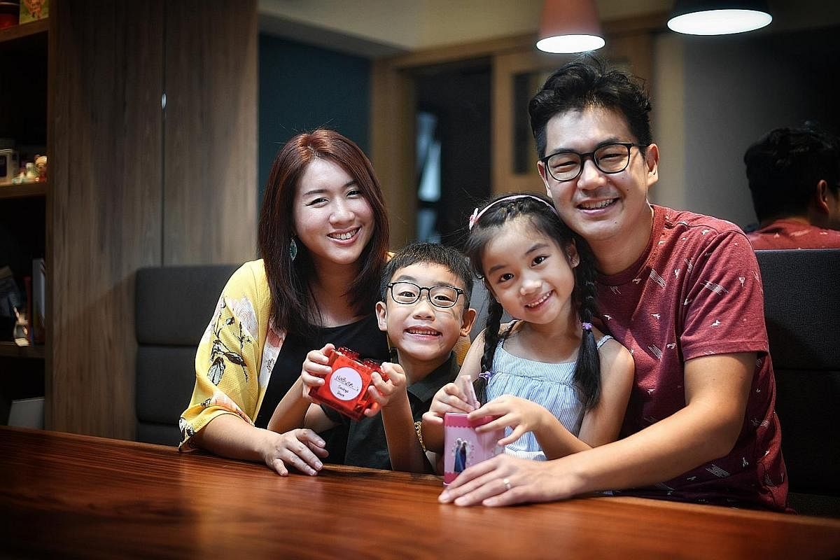Ms Esther Tan (left) and her husband, Mr Elvin Foong, allow their children Nathan and Phoebe to use three $2 notes from their hongbao collection to shop at $2 store Daiso. Ms Angeline Wee (second from left) uses The Game Of Life board game to teach d