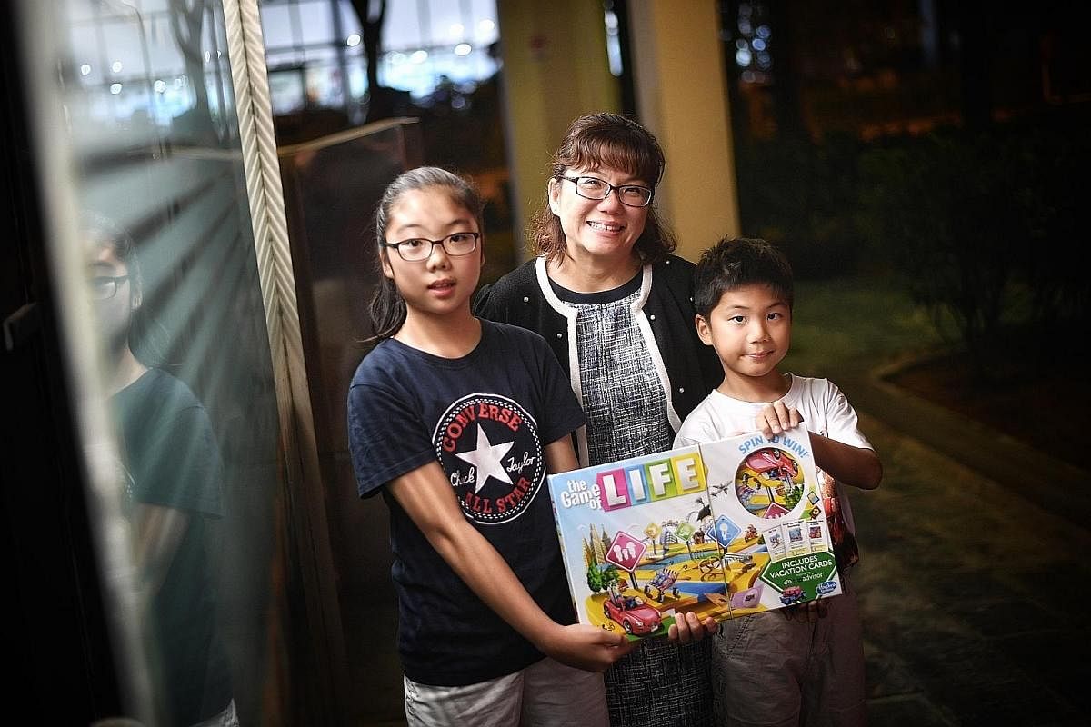 Ms Angeline Wee (second from left) uses The Game Of Life board game to teach daughter Janelle and son Noel about financial issues.