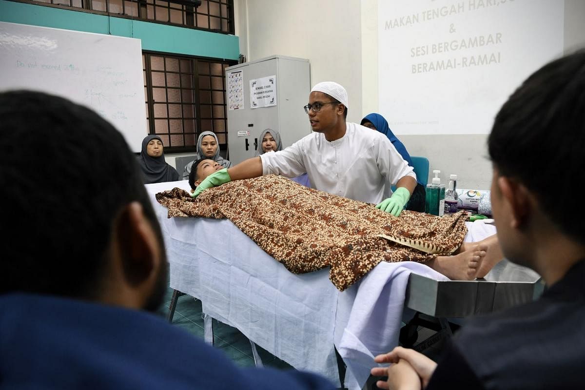 During a practical session on managing death, Mr Razaly, with the help of a volunteer from among his students, demonstrates how to bathe the deceased and conduct prayers as well as other preparations.