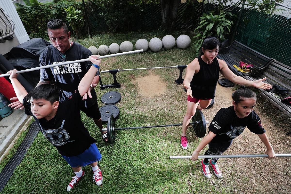 Mr Andrew Johnson and his wife Barbara Chng supervising their eight-year-old twins Brad and Ariel during training in the garden of their Katong home. A warm-up session, which involves mobility workouts and technique drills, is a must before the actua