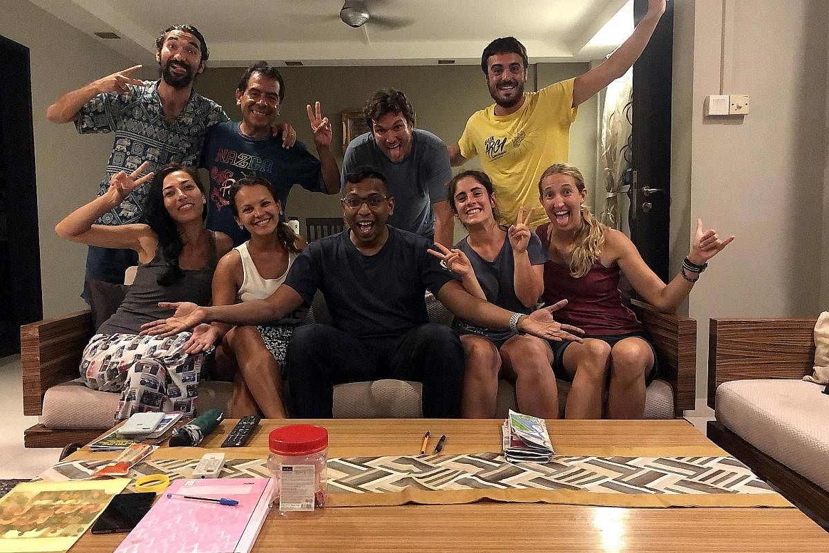 Firefighter Nizar Marican (seated in the centre) hosts up to eight Couchsurfers at a time in his Housing Board flat in Tampines. He has hosted about 300 guests.