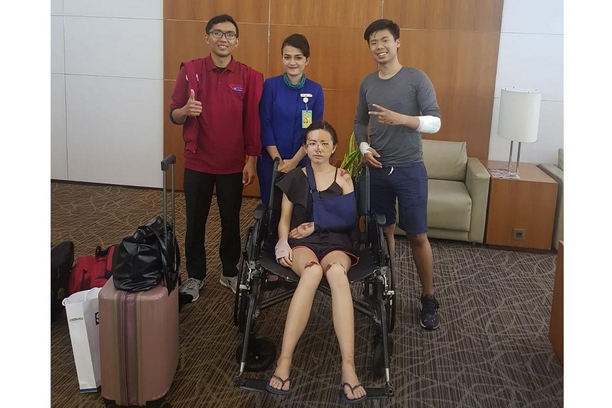 Married Singapore couple Eugene Aathar (far right) and Dolly Ho (seated) were riding a rented scooter in Kuta, Bali, on May 6 when they were robbed, injured and harassed. Staff from the airport (in blue) and MediVac Asia (in red) escorted them at the Ngur