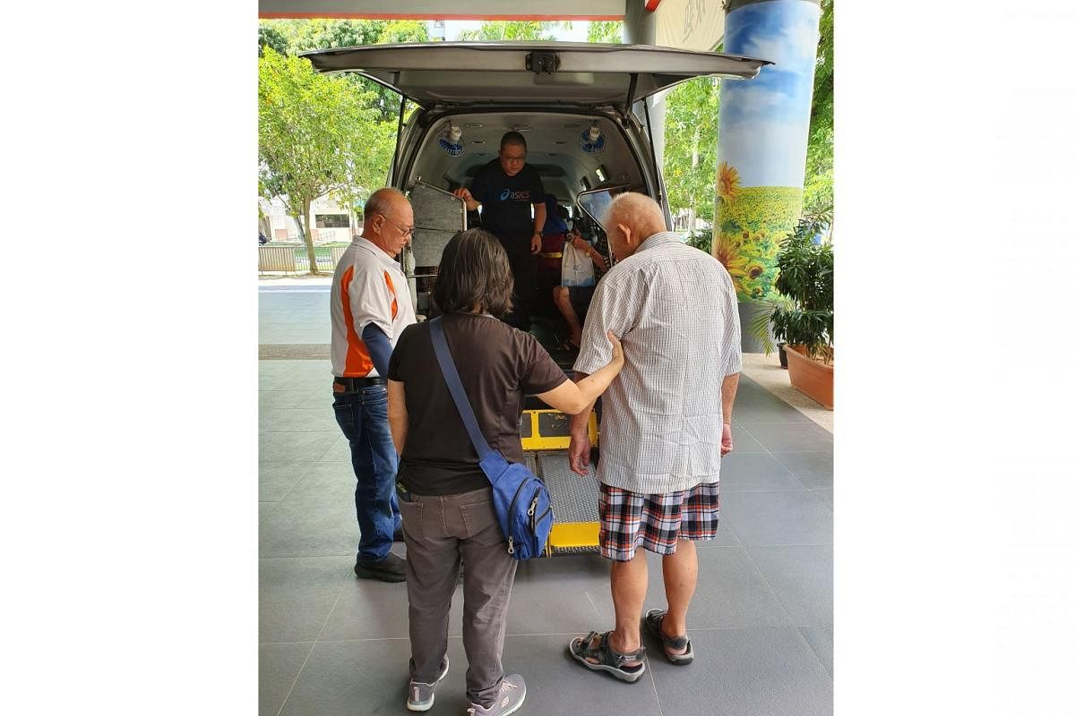 Mr Teng Seng Chye (in beige shirt), being helped by staff members from Awwa. He lives alone in a two-room rental flat in Whampoa and goes to a dementia day care service run by the Tsao Foundation at the Whampoa Community Club. 