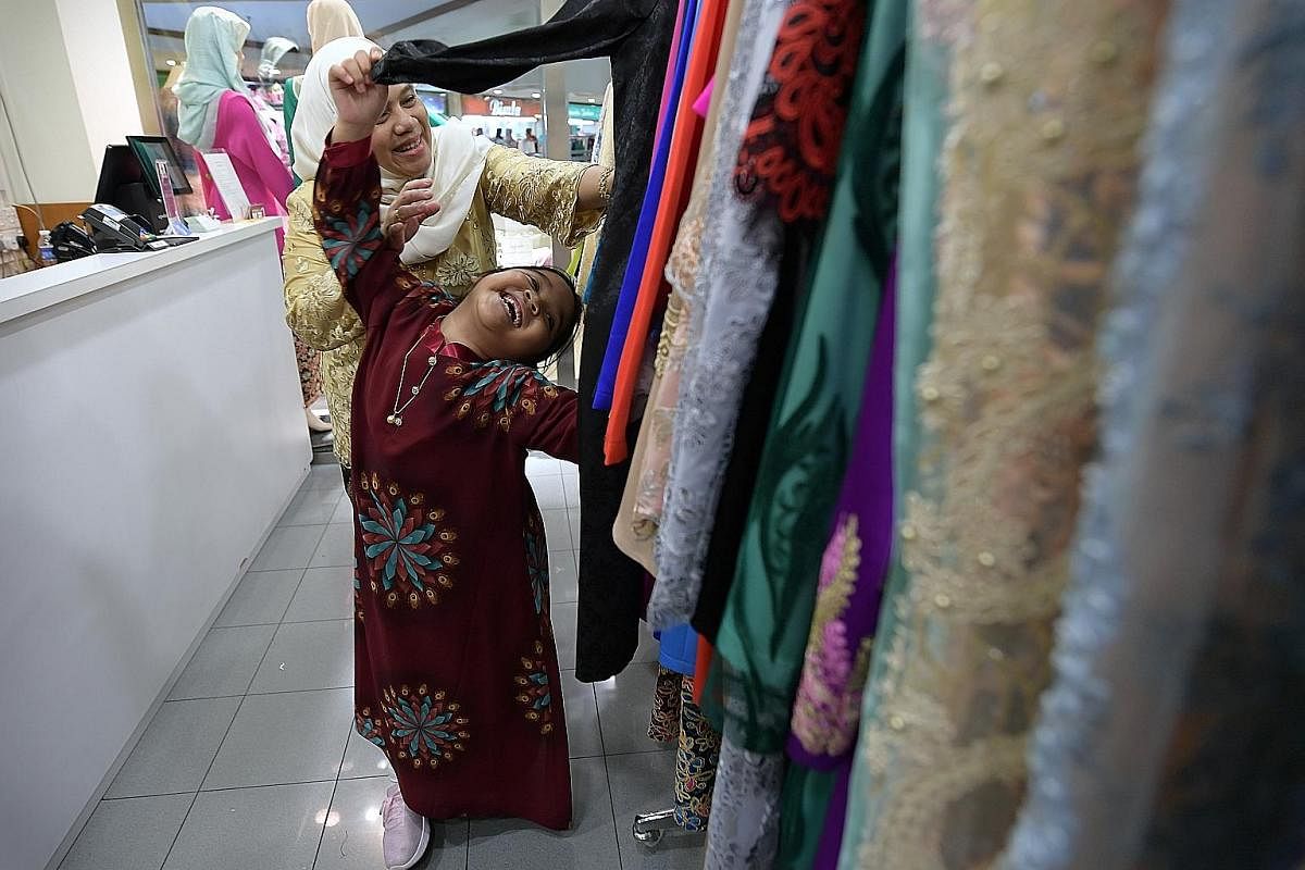 Melati, six, playing among the colourful row of clothing at Bewa Enterprise while her mother Diah Hastuti Pangestu Sagala, 46, browses.