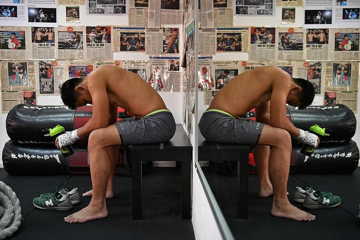 Ridhwan taking a breather after a training session. A corner of his gym is plastered with newspaper articles documenting his boxing journey, which started when he first donned his gloves at 17.