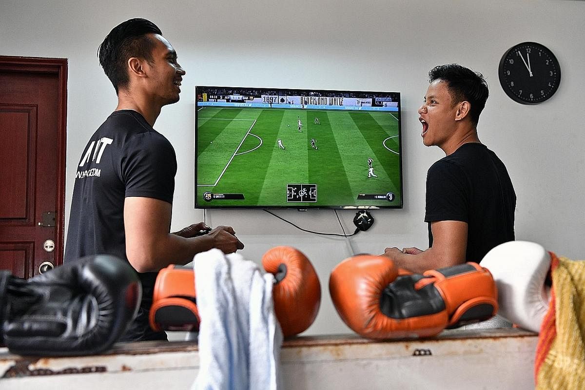 Ridhwan (right) unwinding after a gruelling workout by playing a video game with Mohammad Syazwan, a business partner of their strength and conditioning gym Habit SG.