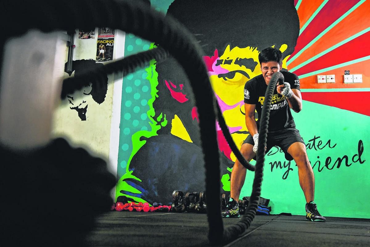 Ridhwan doing a battle rope exercise under the watchful eye of martial arts legend Bruce Lee, painted on the wall behind him. The workout helps to improve endurance in his shoulder muscles. 