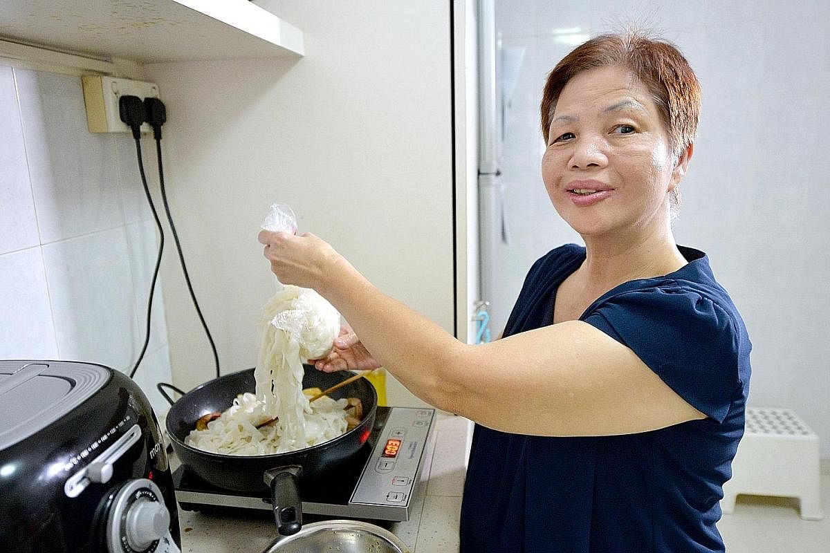 Madam Rosie Wong stir-frying kway teow using her talking induction hob, which vocalises its various functions and temperature settings.