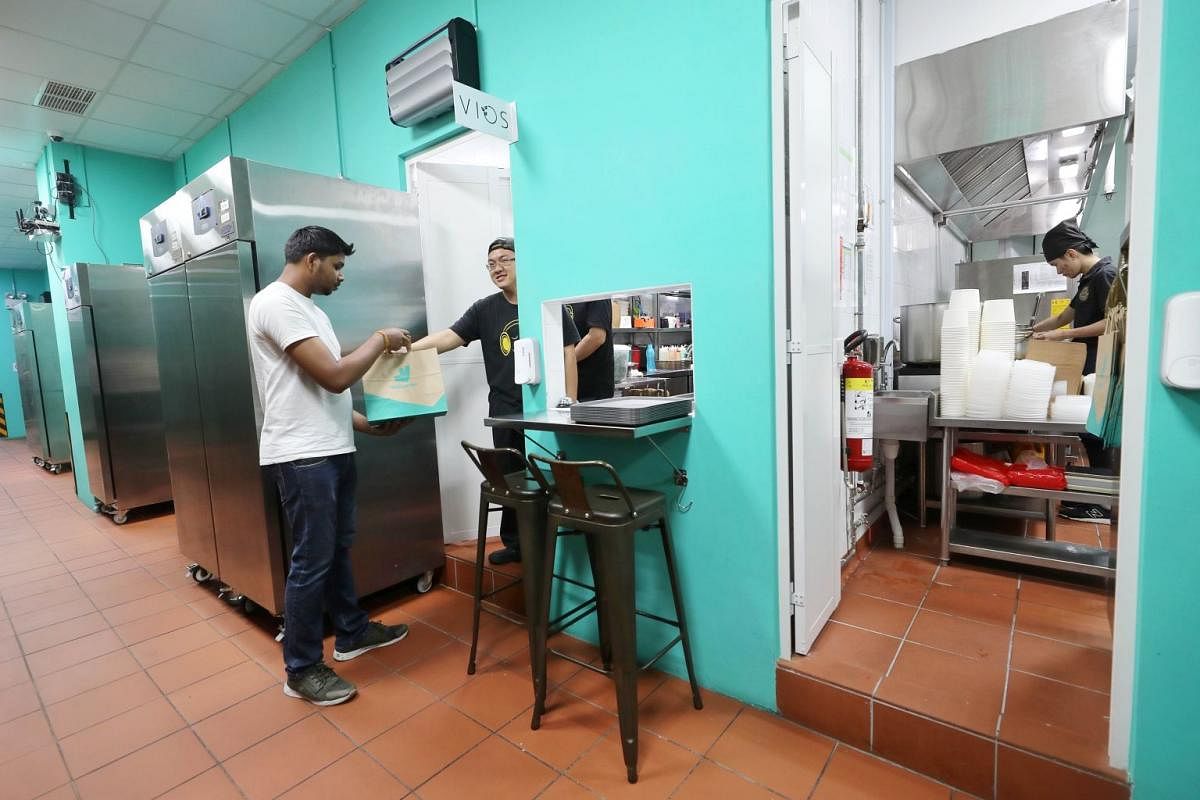 At Deliveroo Food Market at Alice@Mediapolis, a customer orders her food using the tablets provided while a Deliveroo staff collects an order from a restaurant’s kitchen (above).
