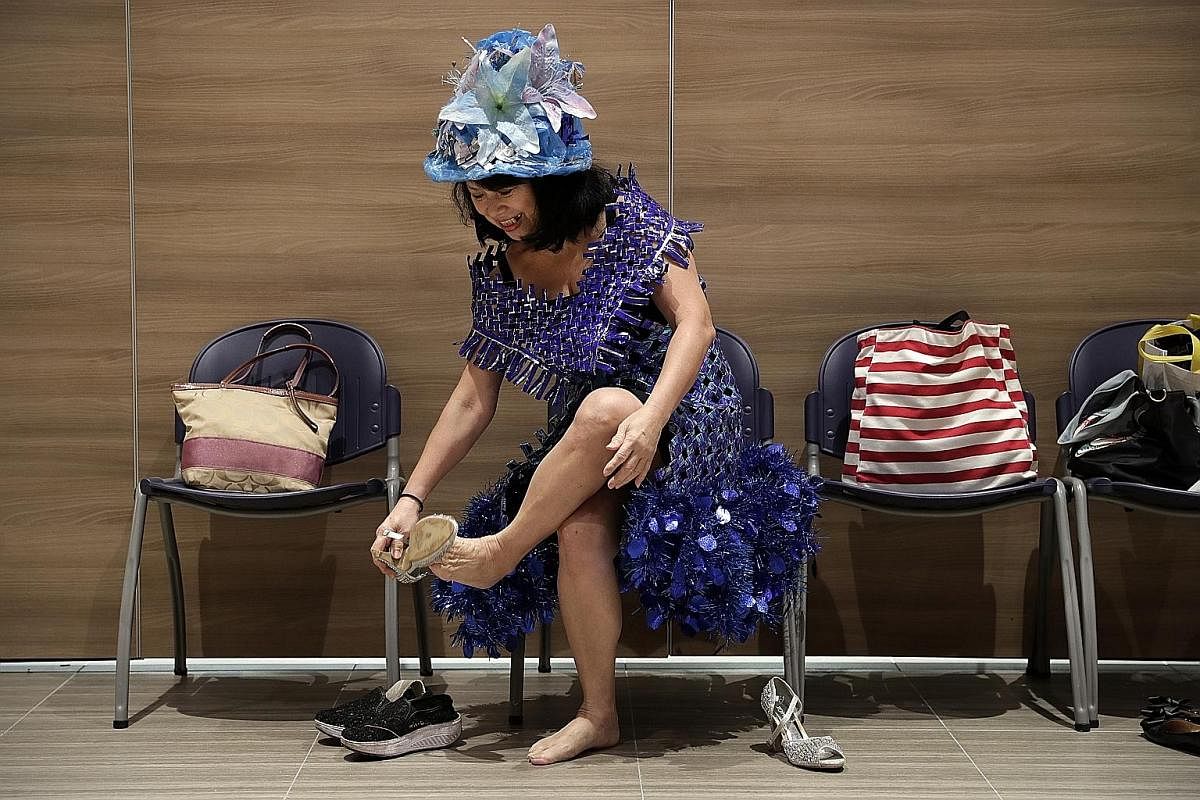 Madam Annie Phua getting ready for a rehearsal. Her blue outfit is woven together from empty packets of Oreo biscuits she had eaten and the hem is lined with leftover Christmas decorations from her home.