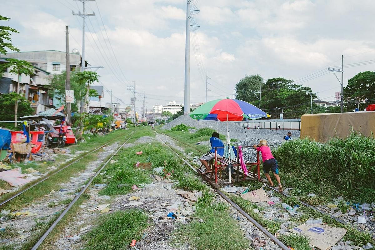 Commuters on a trolley being pushed along a rail line in Manila's Sta Mesa district. It is a risky commute but saves them up to an hour in travelling time.