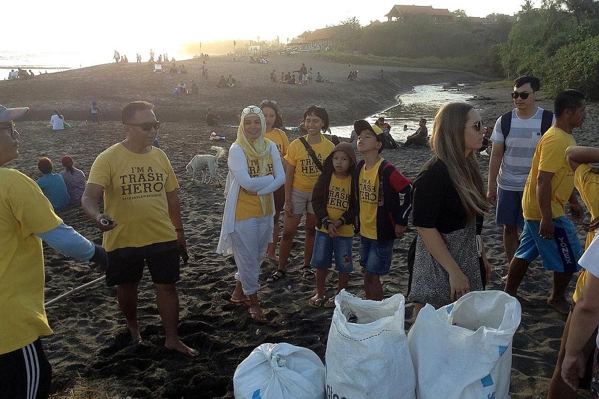 A customer using reusable bags at a supermarket in Bali, where the governor has banned single-use plastic bags. PHOTO: AGENCE FRANCE-PRESSE Ms Fitri (above, centre) at the end of a recent beach clean-up in Bali. More Indonesians are joining the clean