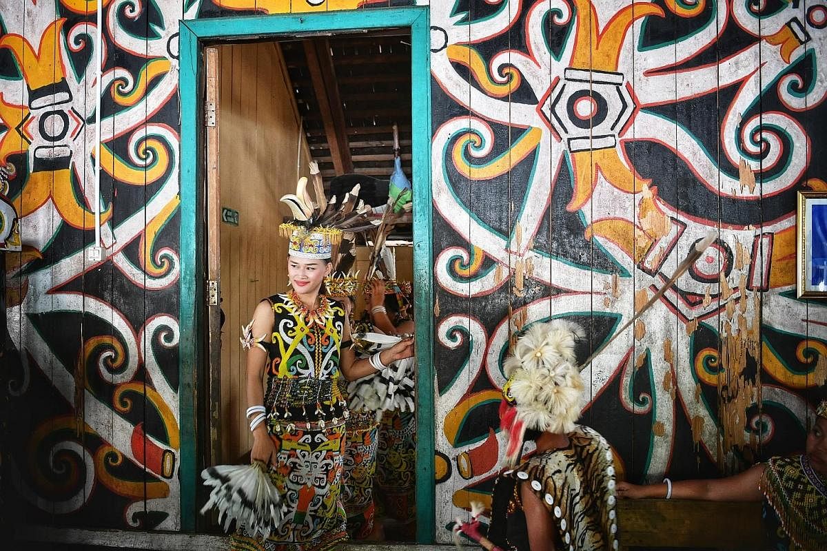 Tourists joining in a traditional Dayak dance, in which huge sticks are used. A performer in traditional clothes. At Pampang Cultural Village, tourists watch cultural performances and shop for Dayak handicrafts. Law graduate Novianti Liq, 24, about t