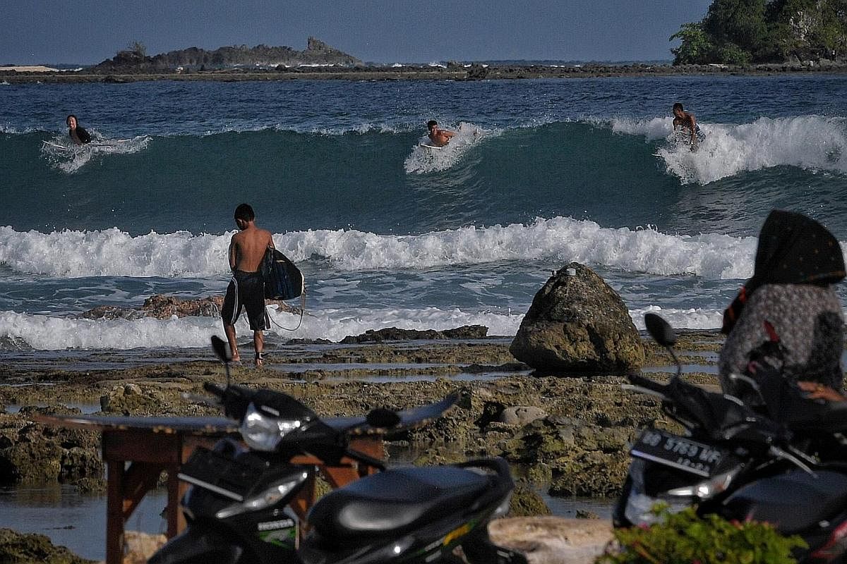Above: Foreign and local surfers preparing to drop in on a wave at Sorake Bay. During the peak surfing season from June to October, up to 40 people at a time can be seen in the water waiting for waves. Right: A local surfer heading home at dusk. Sora