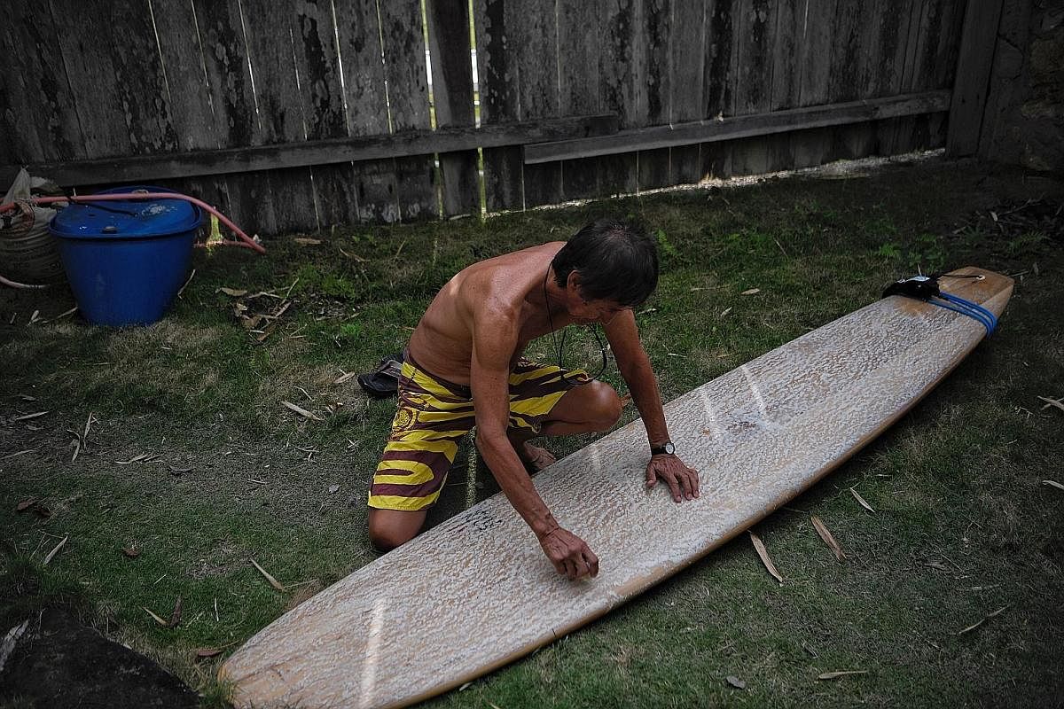 Mr Eu applying wax on his board which measures nearly 3m long. Surfers who use longboards usually surf on more mellow waves, making him a rather peculiar sight in Nias where most surfers ride shorter boards with a more aggressive style. Every morning