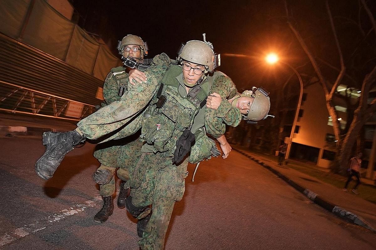 Above: A "casualty" being evacuated to a safe area following a simulated raid. Below: For the most part, the trainees march on little-used roads away from the public eye, but at times they cross roads such as this one in Loyang Avenue. Below right: W