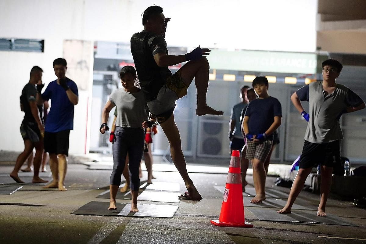 Nine-year-old Kaedee Eng doing pad work with Mr Ace Tan after a warm-up session at Block 813 Yishun Ring Road, where the Fitstop truck is parked for the session. Mr Tan says he tries to make training more fun by joking during class. Ten-year-old Nico