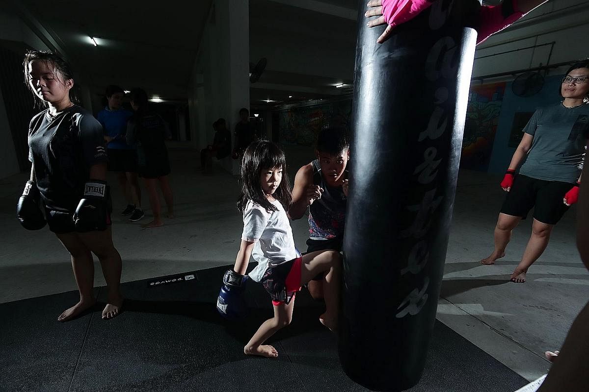Nine-year-old Kaedee Eng doing pad work with Mr Ace Tan after a warm-up session at Block 813 Yishun Ring Road, where the Fitstop truck is parked for the session. Mr Tan says he tries to make training more fun by joking during class. Ten-year-old Nico