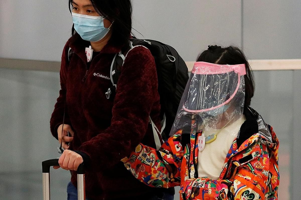 A child wears a self-made mask as she arrives at Hong Kong West Kowloon Station (above) while a pedestrian in Beijing covers up with a mask, shades and hat.