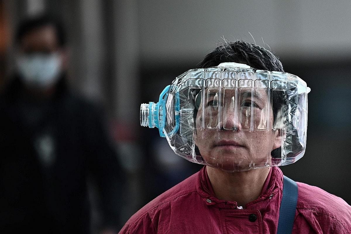A pedestrian in Hong Kong uses a plastic water bottle with a cutout (above) for protection following the virus outbreak in Wuhan while a woman wears a mask in Shanghai. 
