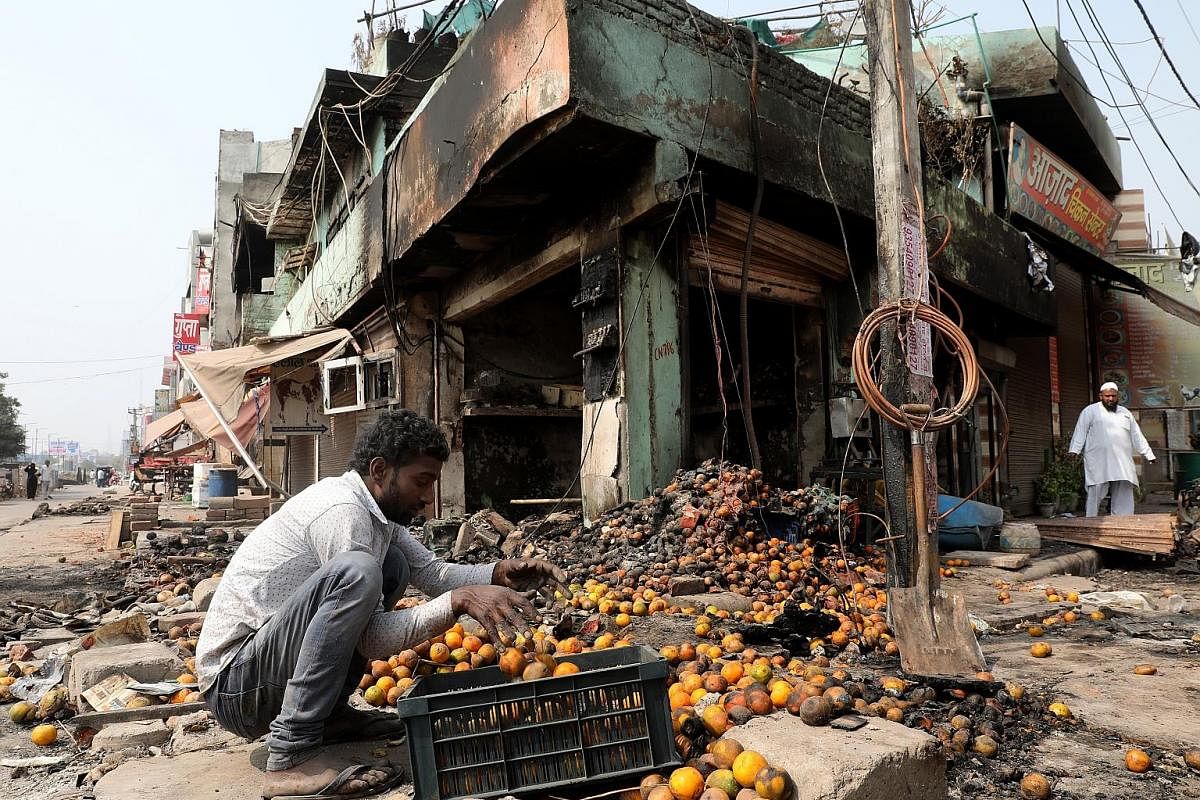 A family sitting amid the ruins of their home, which was set on fire by a mob during the riots. PHOTO: REUTERS A man collecting damaged fruits from a burnt-out area after the Hindu-Muslim riots in New Delhi last week. The riots broke out following cl
