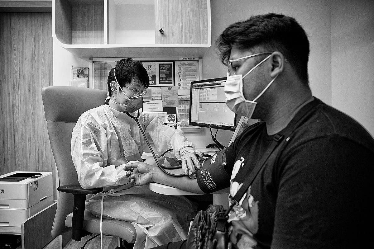 Right: Dr Lam's phone and access pass are kept inside a Ziploc bag to keep them clean. Below: Dr Lam using a blood pressure monitor to assess Mr Muhammad Arrafi Anuar, 23, a full-time national serviceman, in the fever zone.