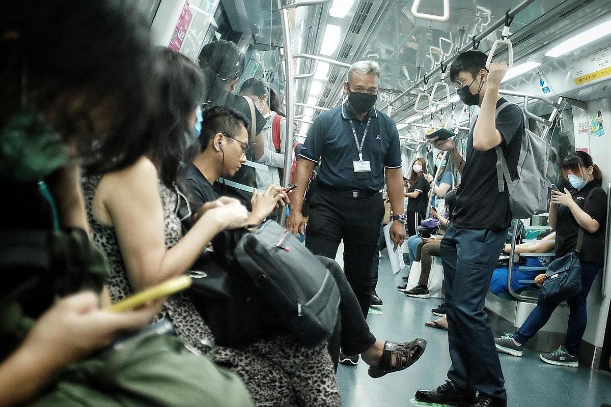 An NParks officer (right) at Bukit Timah Hill ensuring that people carry out safe distancing while exercising. ST PHOTO: MARK CHEONG A Land Transport Authority enforcement officer ensuring safe distancing was being observed on an MRT train yesterday 