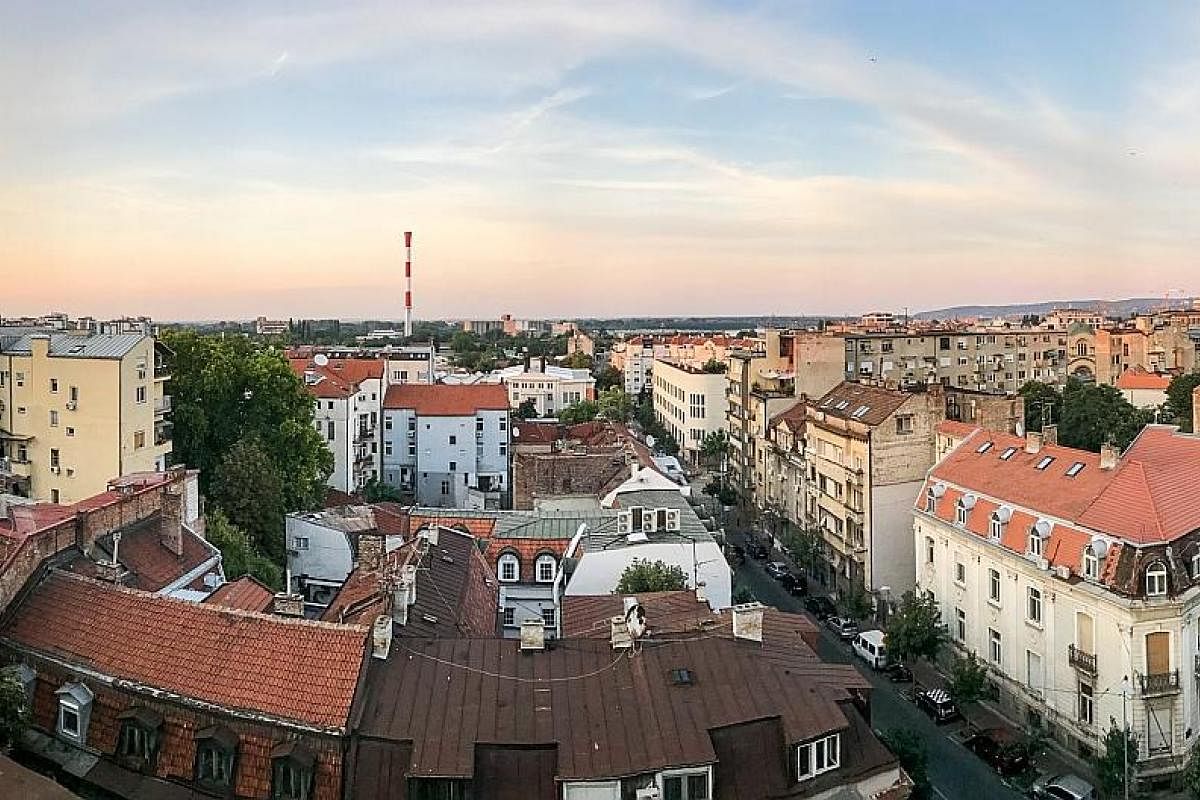 The writer and her boyfriend David Henden. The view from the rooftop of the writer's apartment, featuring Belgrade simmering in the summer sun. (Above, left) The transit hall felt surreal as the morning light sliced through the severe mood of the Doh