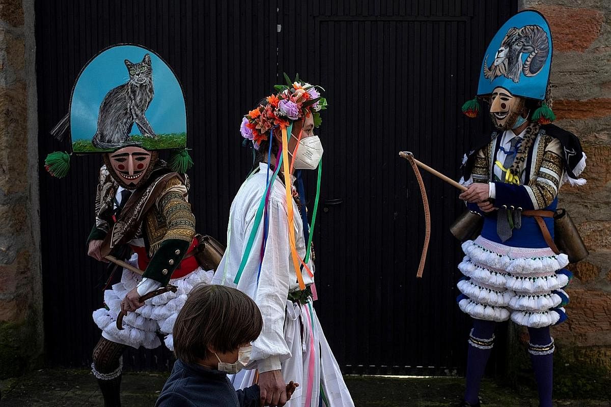 A participant (above) is helped by his parents to dress up for the Entroido festival in the village of Laza, Galicia, north-western Spain. The celebration to commemorate the arrival of spring, which usually sees massive crowds soaking up the merrimen
