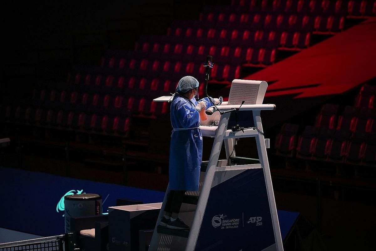 Above: A small crew of officials cleaned the court and sanitised the players' seats before and after each match at the Singapore Tennis Open. ST PHOTOS: ONG WEE JIN Below: Yannick Hanfmann of Germany serving during a men's doubles first round match a