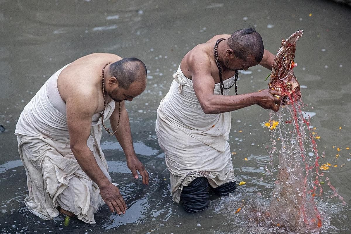 During the festival, priests dip an idol of Madhav Narayan in the river (far left) while devotees practise for worship (left). Some devotees fast for a better life and peace in the country at various temples. Unmarried women also fast to attract a su